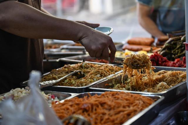 A man prepares food at a curbside canteen in Manila on April 7, 2026. While sticker shock at petrol stations has garnered the biggest headlines since the war in the Middle East forced the partial closure of the Strait of Hormuz, the rising price of LPG has hit the import-dependent archipelago's humble street food vendors hard. (Photo by Jam STA ROSA / AFP) / TO GO WITH AFP STORY: Iran-War-US-Israel-Philippines-economy-LPG, by Pam CASTRO
