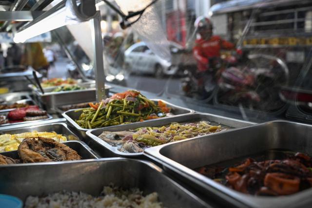 Food is displayed at a curbside canteen in Manila on April 7, 2026. While sticker shock at petrol stations has garnered the biggest headlines since the war in the Middle East forced the partial closure of the Strait of Hormuz, the rising price of LPG has hit the import-dependent archipelago's humble street food vendors hard. (Photo by Jam STA ROSA / AFP) / TO GO WITH AFP STORY: Iran-War-US-Israel-Philippines-economy-LPG, by Pam CASTRO