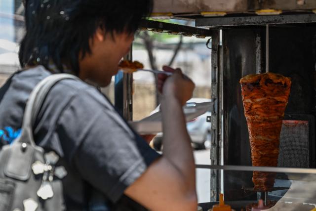 A man eats at a stall in Manila on April 7, 2026. While sticker shock at petrol stations has garnered the biggest headlines since the war in the Middle East forced the partial closure of the Strait of Hormuz, the rising price of LPG has hit the import-dependent archipelago's humble street food vendors hard. (Photo by Jam STA ROSA / AFP) / TO GO WITH AFP STORY: Iran-War-US-Israel-Philippines-economy-LPG, by Pam CASTRO