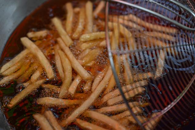 A man cooks french fries at a stall in Manila on April 7, 2026. While sticker shock at petrol stations has garnered the biggest headlines since the war in the Middle East forced the partial closure of the Strait of Hormuz, the rising price of LPG has hit the import-dependent archipelago's humble street food vendors hard. (Photo by Jam STA ROSA / AFP) / TO GO WITH AFP STORY: Iran-War-US-Israel-Philippines-economy-LPG, by Pam CASTRO