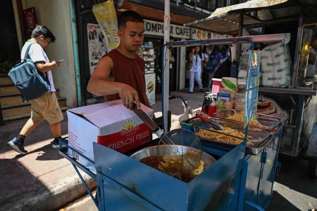 A man cooks french fries at a stall in Manila on April 7, 2026. While sticker shock at petrol stations has garnered the biggest headlines since the war in the Middle East forced the partial closure of the Strait of Hormuz, the rising price of LPG has hit the import-dependent archipelago's humble street food vendors hard. (Photo by Jam STA ROSA / AFP) / TO GO WITH AFP STORY: Iran-War-US-Israel-Philippines-economy-LPG, by Pam CASTRO