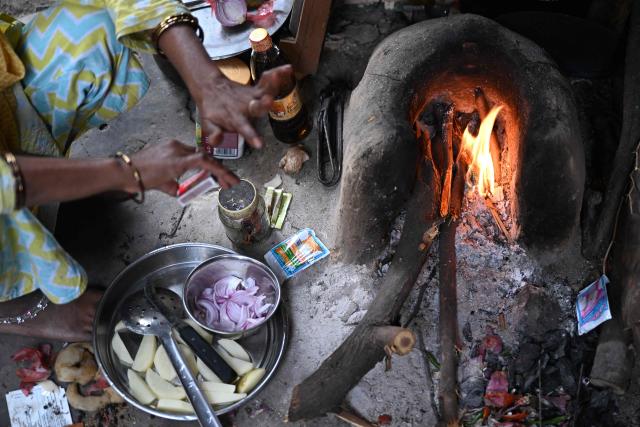 Naseema, a five-month pregnant migrant worker prepares to cook food on a wood-fired earthen stove at her rented shanty in New Delhi on April 9, 2026. Migrant workers in India's capital reeling from an energy crunch sparked by the Mideast war, are weighing whether to leave New Delhi for good. (Photo by Sajjad  HUSSAIN / AFP) / To go with 'India-Politics-Economy-Energy-Migration' FOCUS by Uzmi ATHAR
