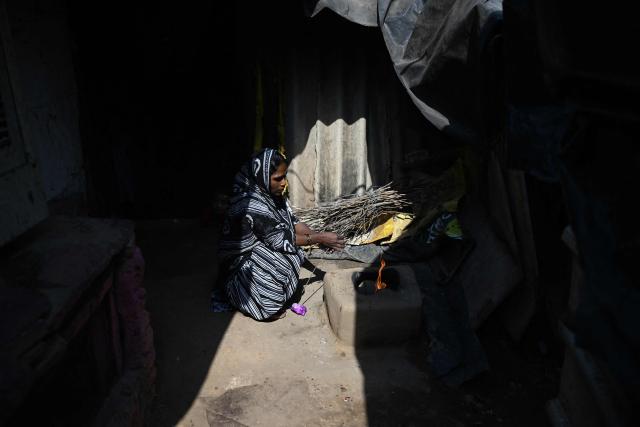 Naseema, a five-month pregnant migrant worker prepares to cook food on a wood-fired earthen stove at her rented shanty in New Delhi on April 9, 2026. Migrant workers in India's capital reeling from an energy crunch sparked by the Mideast war, are weighing whether to leave New Delhi for good. (Photo by Sajjad  HUSSAIN / AFP) / To go with 'India-Politics-Economy-Energy-Migration' FOCUS by Uzmi ATHAR