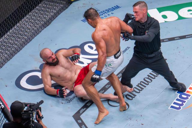 A referee moves in to stop Brazilian Light Heavyweight Paulo Costa (C) as previously undefeated Russian Azamat Murzakanov falls with a Technical Knock Out (TKO) during UFC 327 at Kaseya Center in Miami, on April 11, 2026. (Photo by Jim WATSON / AFP)