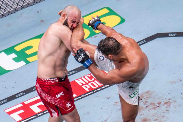 Brazilian Light Heavyweight Paulo Costa (C) kicks previously undefeated Russian Azamat Murzakanov before he falls with a Technical Knock Out (TKO) during UFC 327 at Kaseya Center in Miami, on April 11, 2026. (Photo by Jim WATSON / AFP)