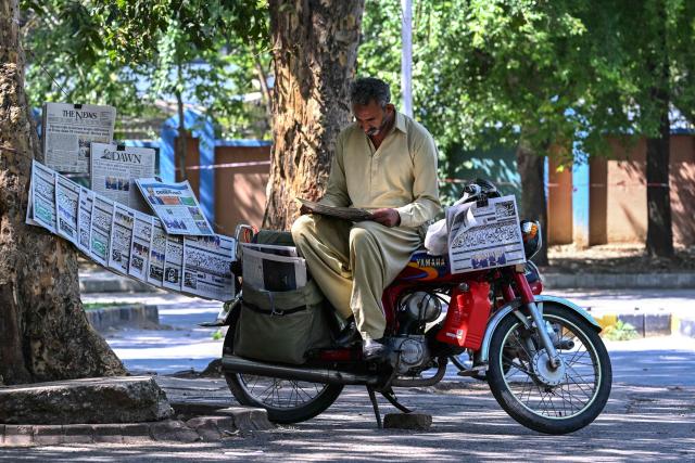 A vendor reads a newspaper displayed on a roadside after the US-Iran peace talks in Islamabad on April 12, 2026. Iran and the United States failed to reach an agreement to end the war in the Middle East, US Vice President JD Vance said on April 12 after marathon talks in Islamabad, adding that he was leaving negotiations after giving Tehran the "final and best offer". (Photo by Farooq NAEEM / AFP)