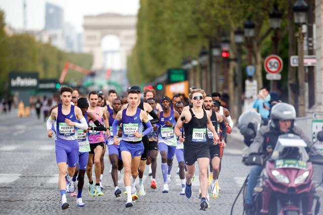 France's athlete Etienne Daguinos (L) and other athletes take the start on the Champs-Elysees avenue during the Paris Marathon, with the Arc de Triomphe in the background, in Paris, on April 12, 2026. (Photo by Ian LANGSDON / AFP)