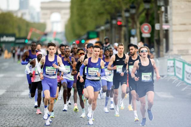 France's athlete Etienne Daguinos (L) and other athletes take the start on the Champs-Elysees avenue during the Paris Marathon, with the Arc de Triomphe in the background, in Paris, on April 12, 2026. (Photo by Ian LANGSDON / AFP)