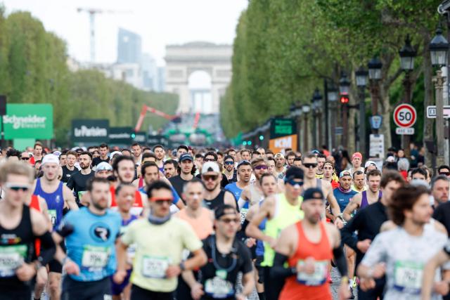 Athletes take the start on the Champs-Elysees avenue during the Paris Marathon, with the Arc de Triomphe in the background, in Paris, on April 12, 2026. (Photo by Ian LANGSDON / AFP)