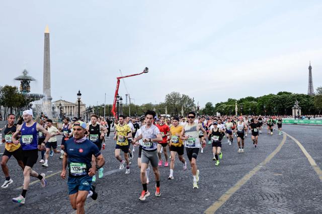 Atheletes run past the Place de la Concorde, with the National Assembly (L) and the Eiffel Tower in the background, during the Paris Marathon, in Paris, on April 12, 2026. (Photo by STEPHANE DE SAKUTIN / AFP)