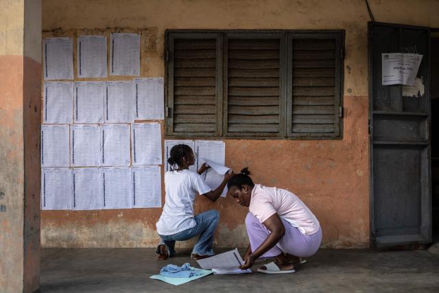 Electoral officials put up the voters’ roll at a primary school serving as a polling station in Cotonou, on April 12, 2026 during Benin's presidential election. (Photo by OLYMPIA DE MAISMONT / AFP)