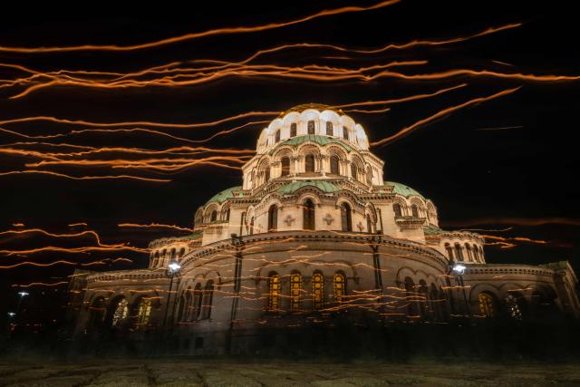 TOPSHOT - This long exposure effect photograph shows lights from candles hold by Bulgarian Orthodox worshippers during a midnight Easter mass in front of the Saint Alexander Nevsky Cathedral in Sofia on early April 12, 2026. (Photo by Nikolay DOYCHINOV / AFP)