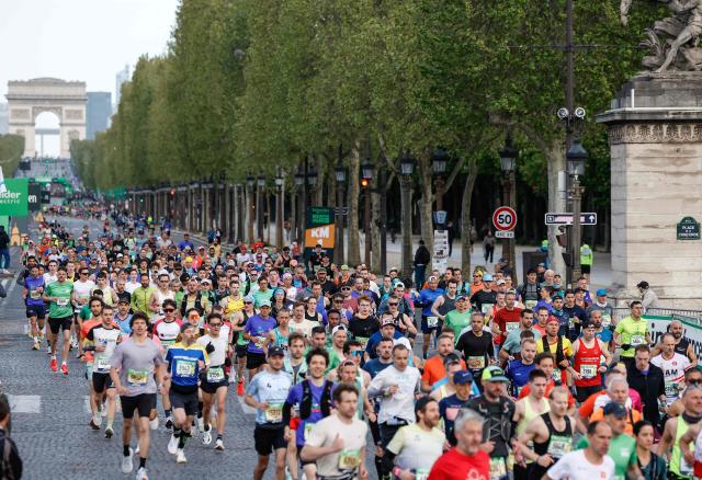 Athletes take the start on the Champs-Elysees avenue during the Paris Marathon, with the Arc de Triomphe in the background, in Paris, on April 12, 2026. (Photo by Ian LANGSDON / AFP)