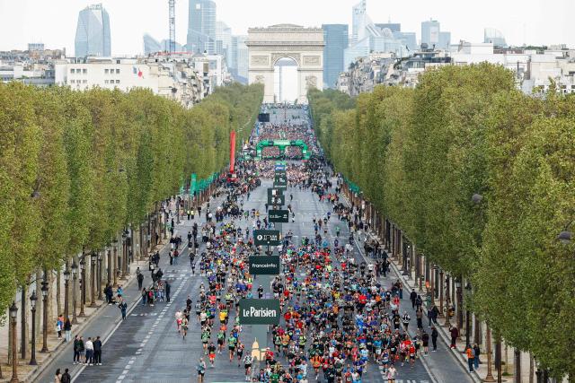 Athletes take the start on the Champs-Elysees avenue during the Paris Marathon, with the Arc de Triomphe in the background, in Paris, on April 12, 2026. (Photo by Ian LANGSDON / AFP)