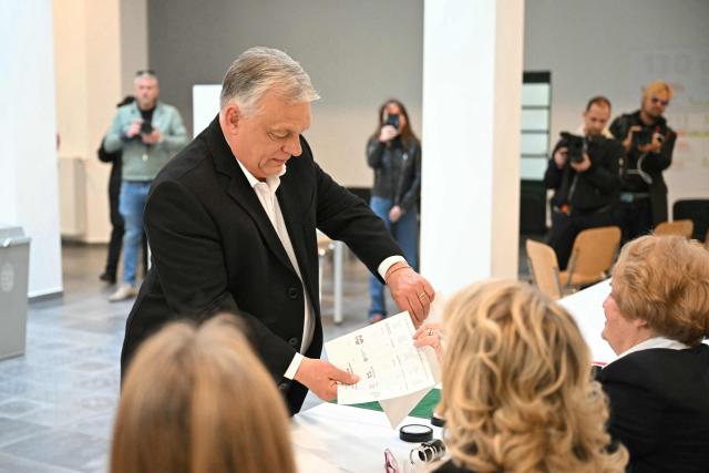 Hungarian Prime Minister Viktor Orban receives his ballot papers at a polling station set up in a school of the 12th district in Budapest during a general election in Hungary, on April 12, 2026. The vote could end Hungarian Prime Minister Viktor Orban's 16-year stint in power as the EU's longest serving current leader and a self-decribed "thorn" in the bloc's side. (Photo by Attila KISBENEDEK / AFP)