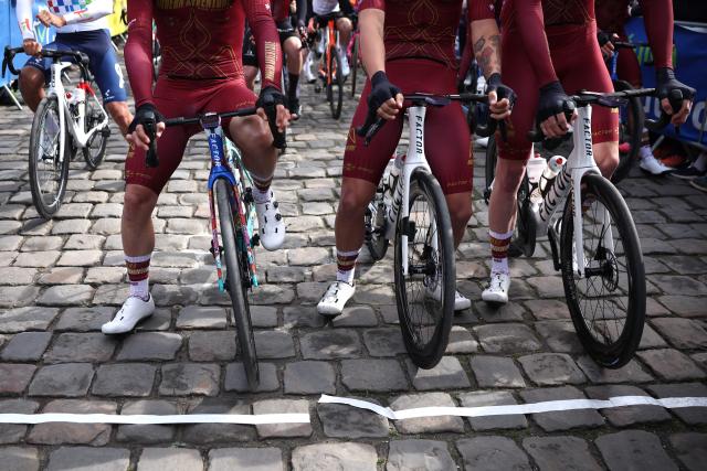 Riders wait on cobblestone road at the start of the 123rd edition of the Paris-Roubaix one-day classic cycling race, 258.3 km between Compiègne and Roubaix, northern France, on April 12, 2026. (Photo by Anne-Christine POUJOULAT / AFP)