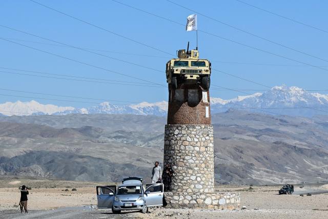 People take photographs with a former US military Humvee displayed atop a tower in the Naghlu area of Surobi district, Kabul province, on April 12, 2026. (Photo by Wakil KOHSAR / AFP)