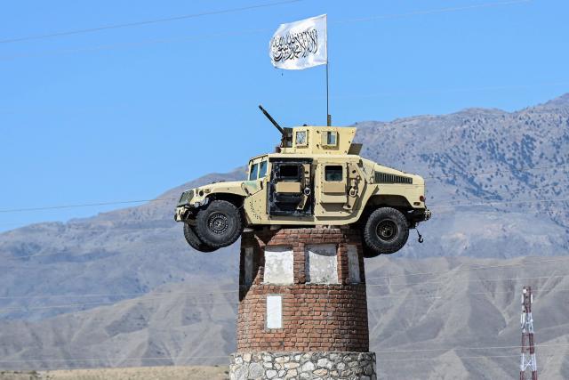 A former US military Humvee with the Taliban flag flying over it is displayed atop a tower in the Naghlu area of Surobi district, Kabul province, on April 12, 2026. (Photo by Wakil KOHSAR / AFP)