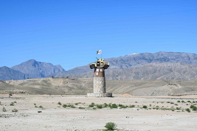 A former US military Humvee with the Taliban flag flying over it is displayed atop a tower in the Naghlu area of Surobi district, Kabul province, on April 12, 2026. (Photo by Wakil KOHSAR / AFP)