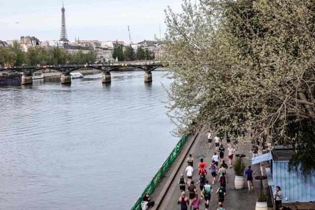 Participants run along the docks of the Seine river, with the Eiffel Tower in the background, during the Paris Marathon, in Paris, on April 12, 2026. (Photo by STEPHANE DE SAKUTIN / AFP)