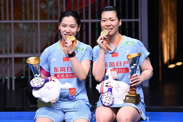 Gold medallists China´s Li Yijing (L) and Luo Xumin celebrate on the podium during the award ceremony for women's doubles final match at the Badminton Asia Championship in Ningbo, eastern China's Zhejiang province on April 12, 2026. (Photo by CN-STR / AFP) / China OUT