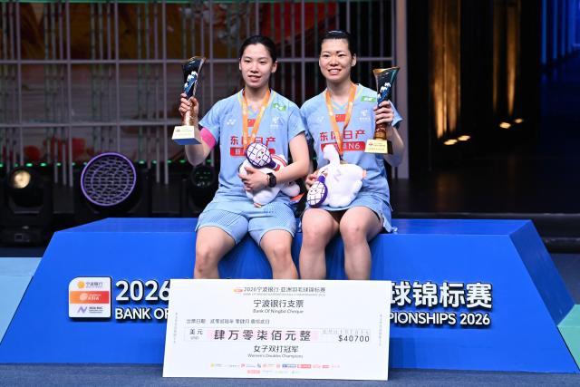 Gold medallists China´s Li Yijing (L) and Luo Xumin celebrate on the podium during the award ceremony for women's doubles final match at the Badminton Asia Championship in Ningbo, eastern China's Zhejiang province on April 12, 2026. (Photo by CN-STR / AFP) / China OUT