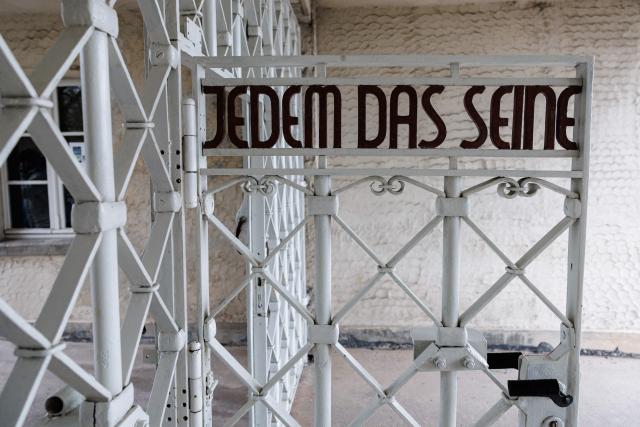 The main gate with the inscription "Jedem das Seine" (To Each His Own) is pictured at the memorial site of the former Nazi concentration camp Buchenwald on April 12, 2026, prior to the commemoration ceremony to mark the 81th anniversary of the liberation of the Buchenwald Nazi concentration camp at the camp's memorial site near Weimar, eastern Germany. From 1937 to 1945, almost 280,000 victims of the Nazis were imprisoned in Buchenwald concentration camp and its satellite camps; more than 56,000 were murdered or died as a result of inhumane conditions. Among the prisoners were Jews, Roma, domestic political opponents of the Nazis, and forced laborers from Eastern Europe. Buchenwald is one of the most symbolically significant and best-known former concentration camps in Germany. (Photo by JENS SCHLUETER / AFP)