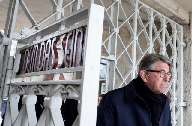 German State Minister for Culture and Media Wolfram Weimer walks through the main gate with the inscription "Jedem das Seine" (To Each His Own) as he arrives at the memorial site of the former Nazi concentration camp Buchenwald on April 12, 2026, to attend the commemoration ceremony to mark the 81th anniversary of the liberation of the Buchenwald Nazi concentration camp at the camp's memorial site near Weimar, eastern Germany. From 1937 to 1945, almost 280,000 victims of the Nazis were imprisoned in Buchenwald concentration camp and its satellite camps; more than 56,000 were murdered or died as a result of inhumane conditions. Among the prisoners were Jews, Roma, domestic political opponents of the Nazis, and forced laborers from Eastern Europe. Buchenwald is one of the most symbolically significant and best-known former concentration camps in Germany. (Photo by Jens SCHLUETER / AFP)