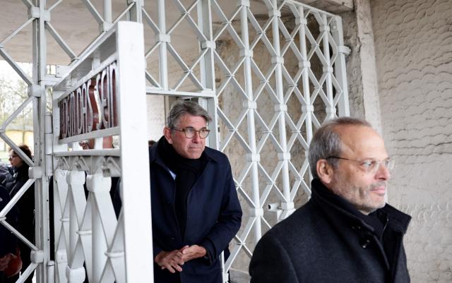 German State Minister for Culture and Media Wolfram Weimer (C) and the Federal Government's Commissioner for Jewish Life in Germany and the Fight against Antisemitism Felix Klein (R) walk through the main gate with the inscription "Jedem das Seine" (To Each His Own) as they arrive at the memorial site of the former Nazi concentration camp Buchenwald on April 12, 2026, to attend the commemoration ceremony to mark the 81th anniversary of the liberation of the Buchenwald Nazi concentration camp at the camp's memorial site near Weimar, eastern Germany. From 1937 to 1945, almost 280,000 victims of the Nazis were imprisoned in Buchenwald concentration camp and its satellite camps; more than 56,000 were murdered or died as a result of inhumane conditions. Among the prisoners were Jews, Roma, domestic political opponents of the Nazis, and forced laborers from Eastern Europe. Buchenwald is one of the most symbolically significant and best-known former concentration camps in Germany. (Photo by Jens SCHLUETER / AFP)
