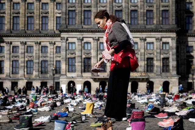 A member of the putblic walks amongst children's shoes layed out on Dam Square during a memorial protest organised by Plant an Olive Tree group for child victims in Gaza, in Amsterdam, on April 12, 2026. (Photo by Ramon van Flymen / ANP / AFP) / Netherlands OUT