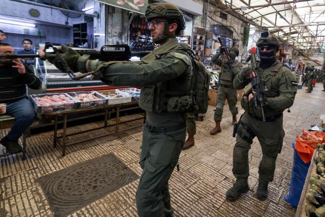 Armed Israeli soldiers patrol through the market in the Old City of Nablus, in the northern Israeli-occupied Palestinian West Bank on April 12, 2026. Israeli police said on April 12, eight suspects were arrested after an overnight attack by Israeli civilians on a Palestinian village in the occupied West Bank. Violence in the West Bank, which Israel has occupied since 1967, has risen sharply since the October 7, 2023 Hamas attack on Israel triggered the Gaza war. (Photo by JAAFAR ASHTIYEH / AFP)