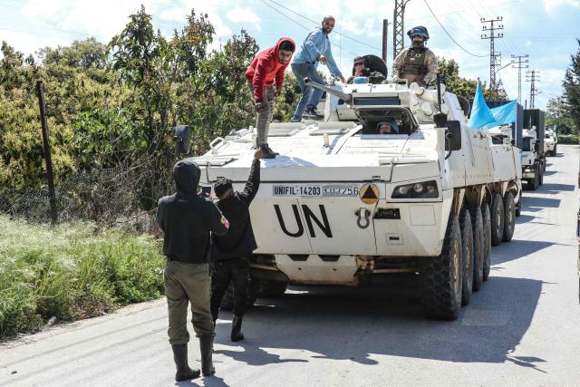 Civilians climb onto a United Nations Interim Force in Lebanon (UNIFIL) armored vehicle to take a selfie as they patrol the road in the southern Lebanese village of Tair Debba on April 12, 2026. Dozens of countries contributing troops to the UN peacekeeping force in Lebanon called on April 9, 2026, for a cessation of hostilities, after three blue helmets were killed as Israel and Hezbollah traded strikes. (Photo by Kawnat HAJU / AFP)