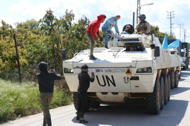 Civilians climb onto a United Nations Interim Force in Lebanon (UNIFIL) armored vehicle to take a selfie as they patrol the road in the southern Lebanese village of Tair Debba on April 12, 2026. Dozens of countries contributing troops to the UN peacekeeping force in Lebanon called on April 9, 2026, for a cessation of hostilities, after three blue helmets were killed as Israel and Hezbollah traded strikes. (Photo by Kawnat HAJU / AFP)