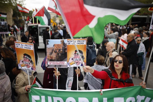 A woman holds a Palestinian flag as protesters take part in a rally against the Yadan bill, which aims to combat new forms of anti-Semitism, in Paris on April 12, 2026. The proposed bill, named after French lawmaker from the presidential camp Caroline Yadan and will be debated next April 16 and 17, aims to combat "new forms" of anti-Semitism and has met with strong reservations. Its opponents, particularly on the left, argue that it would threaten freedom of expression and perpetuate a conflation of Jews and Israel. (Photo by Ian LANGSDON / AFP)