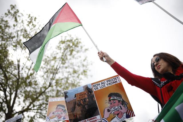 A woman holds a Palestinian flag as protesters take part in a rally against the Yadan bill, which aims to combat new forms of anti-Semitism, in Paris on April 12, 2026. The proposed bill, named after French lawmaker from the presidential camp Caroline Yadan and will be debated next April 16 and 17, aims to combat "new forms" of anti-Semitism and has met with strong reservations. Its opponents, particularly on the left, argue that it would threaten freedom of expression and perpetuate a conflation of Jews and Israel. (Photo by Ian LANGSDON / AFP)