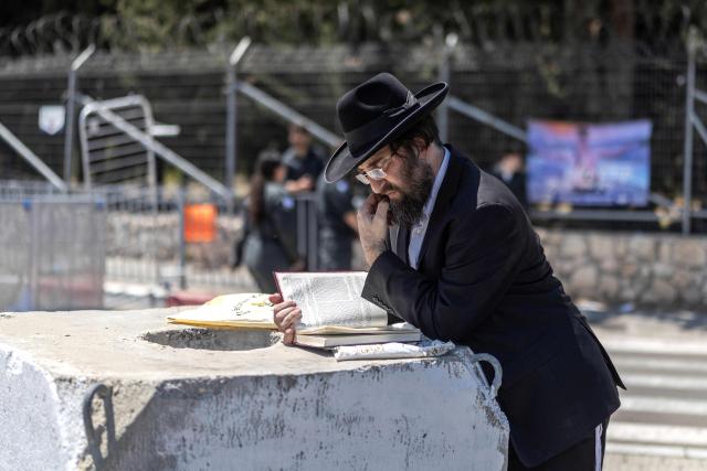 An ultra-Orthodox Jewish man reads the Torah during a protest against conscription of the ultra-Orthodox at the entrance to Tel Hashomer, the central recruitment centre of the Israeli Army, in Ramat-Gan on April 12, 2026. Israel’s Prime Minister, who depends on his ultra-Orthodox party allies to maintain power, has employed a range of tactics to delay the adoption of legislation that would allow the enlistment of ultra-Orthodox Jews, who are largely exempt from military service. Under a ruling established at the country’s creation in 1948—when the ultra-Orthodox community was small—men who devote themselves full-time to the study of sacred Jewish texts receive a de facto exemption. (Photo by Ilia YEFIMOVICH / AFP) / 