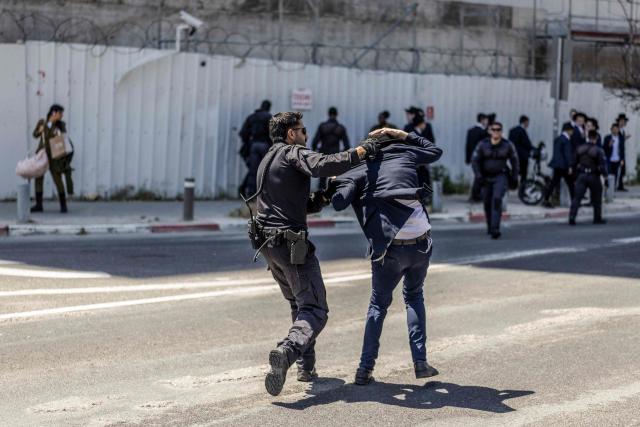 Israeli police restrains an ultra-Orthodox Jewish man during a protest against conscription of the ultra-Orthodox at the entrance to Tel Hashomer, the central recruitment centre of the Israeli Army, in Ramat-Gan on April 12, 2026. Israel’s Prime Minister, who depends on his ultra-Orthodox party allies to maintain power, has employed a range of tactics to delay the adoption of legislation that would allow the enlistment of ultra-Orthodox Jews, who are largely exempt from military service. Under a ruling established at the country’s creation in 1948—when the ultra-Orthodox community was small—men who devote themselves full-time to the study of sacred Jewish texts receive a de facto exemption. (Photo by Ilia YEFIMOVICH / AFP) / 