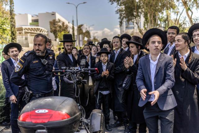 Ultra-Orthodox Jews, who are largely exempt from military service, protest against conscription at the entrance to Tel Hashomer, the central recruitment centre of the Israeli Army, in Ramat-Gan on April 12, 2026. Israel’s Prime Minister, who depends on his ultra-Orthodox party allies to maintain power, has employed a range of tactics to delay the adoption of legislation that would allow the enlistment of ultra-Orthodox Jews, who are largely exempt from military service. Under a ruling established at the country’s creation in 1948—when the ultra-Orthodox community was small—men who devote themselves full-time to the study of sacred Jewish texts receive a de facto exemption. (Photo by Ilia YEFIMOVICH / AFP) / 