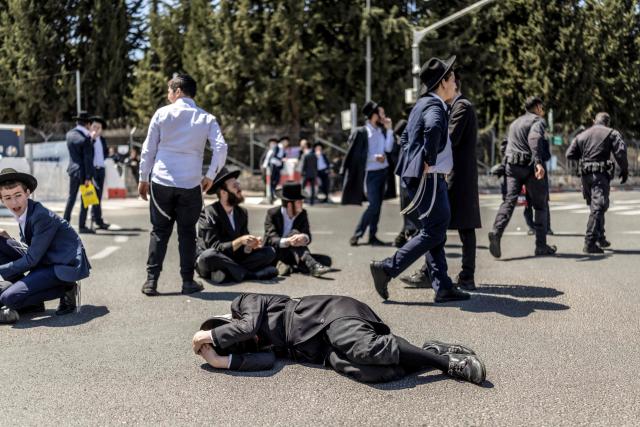 Ultra-Orthodox Jews, who are largely exempt from military service, gather during a protest against conscription at the entrance to Tel Hashomer, the central recruitment centre of the Israeli Army, in Ramat-Gan on April 12, 2026. Israel’s Prime Minister, who depends on his ultra-Orthodox party allies to maintain power, has employed a range of tactics to delay the adoption of legislation that would allow the enlistment of ultra-Orthodox Jews, who are largely exempt from military service. Under a ruling established at the country’s creation in 1948—when the ultra-Orthodox community was small—men who devote themselves full-time to the study of sacred Jewish texts receive a de facto exemption. (Photo by Ilia YEFIMOVICH / AFP) / 