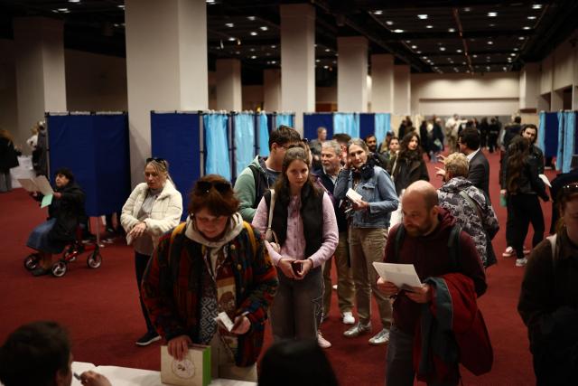Voters queue to collect their ballot papers as they vote in the Hungarian election inside the polling station set up at a hotel in west London, on April 12, 2026. The vote could end Hungarian Prime Minister Viktor Orban's 16-year stint in power as the EU's longest serving current leader and a self-decribed "thorn" in the bloc's side. (Photo by Henry Nicholls / AFP)