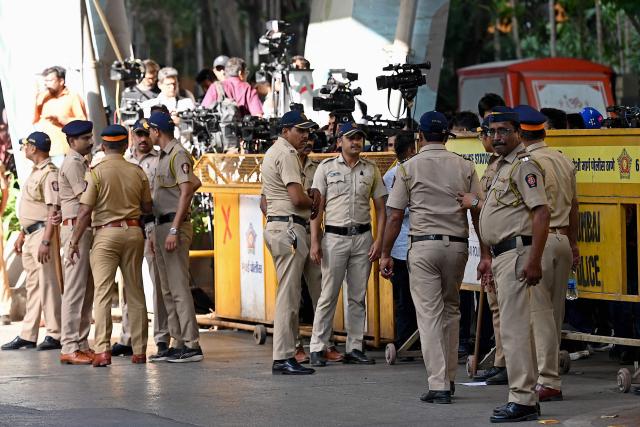 Police and media personnel stand outside the barricaded residence of late Bollywood playback singer Asha Bhosle in Mumbai on April 12, 2026. Legendary Indian playback singer Bhosle, whose voice defined Bollywood music through the 1970s and 80s, died on April 12 in Mumbai aged 92, her family said. (Photo by Sujit JAISWAL / AFP)