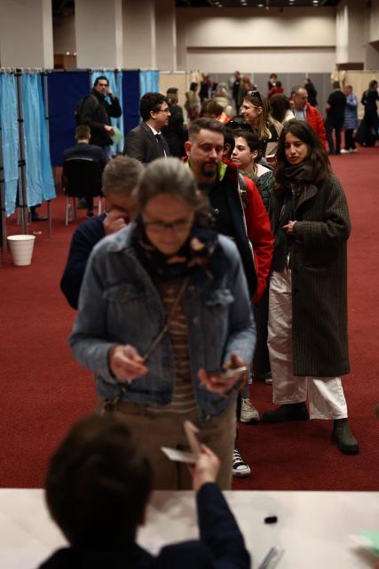 Voters queue to collect their ballot papers as they vote in the Hungarian election inside the polling station set up at a hotel in west London, on April 12, 2026. The vote could end Hungarian Prime Minister Viktor Orban's 16-year stint in power as the EU's longest serving current leader and a self-decribed "thorn" in the bloc's side. (Photo by Henry Nicholls / AFP)