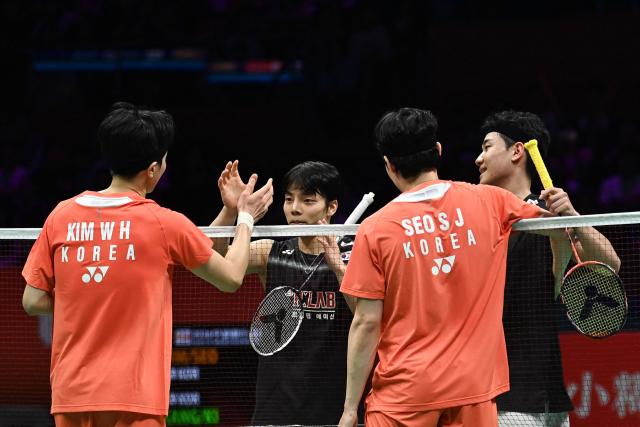 South Korea´s Kim Won-ho (L) and Seo Seung-jae (2/R) shake hands with South Korea´s Kang Min-hyuk (R) and Ki Dong-ju (2/L) during their men's doubles final match at the Badminton Asia Championship in Ningbo, eastern China's Zhejiang province on April 12, 2026. (Photo by CN-STR / AFP) / China OUT