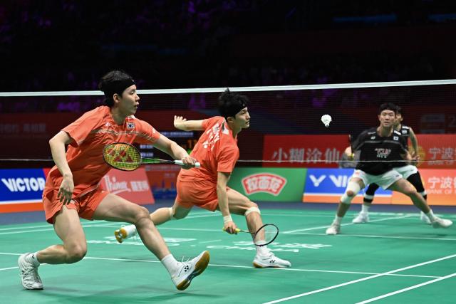 South Korea´s Kim Won-ho (2/L) and Seo Seung-jae (L) hit a return to South Korea´s Kang Min-hyuk (2/R) and Ki Dong-ju (R) during their men's doubles final match at the Badminton Asia Championship in Ningbo, eastern China's Zhejiang province on April 12, 2026. (Photo by CN-STR / AFP) / China OUT
