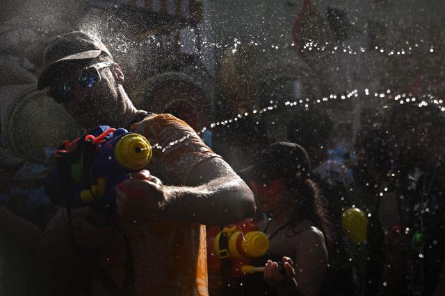 Revellers take part in mass water fights on the eve of the Songkran, or Thai New Year, on Khao San Road in Bangkok on April 12, 2026. (Photo by Lillian SUWANRUMPHA / AFP)