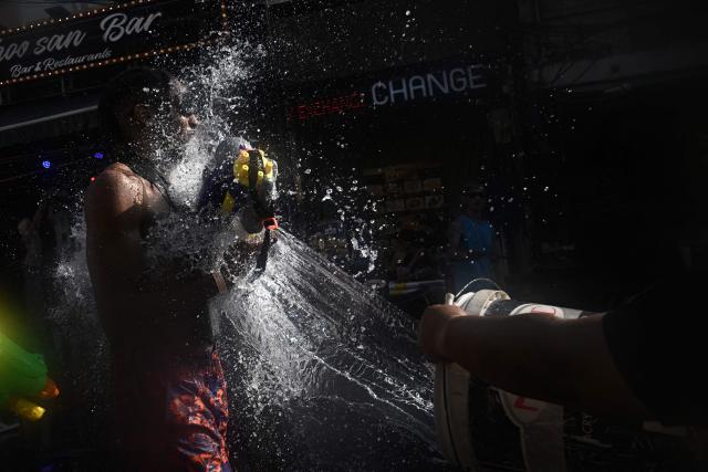 Revellers take part in mass water fights on the eve of the Songkran, or Thai New Year, on Khao San Road in Bangkok on April 12, 2026. (Photo by Lillian SUWANRUMPHA / AFP)