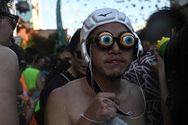 Revellers take part in mass water fights on the eve of the Songkran, or Thai New Year, on Khao San Road in Bangkok on April 12, 2026. (Photo by Lillian SUWANRUMPHA / AFP)