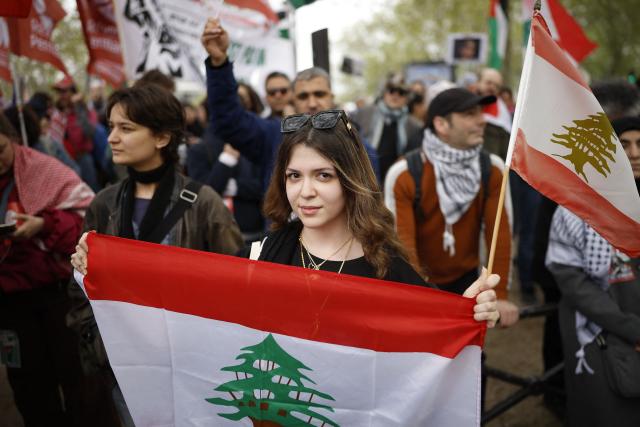 A woman holds a Lebanese flag as protesters take part in a rally against the Yadan bill, which aims to combat new forms of anti-Semitism, in Paris on April 12, 2026. The proposed bill, named after French lawmaker from the presidential camp Caroline Yadan and will be debated next April 16 and 17, aims to combat "new forms" of anti-Semitism and has met with strong reservations. Its opponents, particularly on the left, argue that it would threaten freedom of expression and perpetuate a conflation of Jews and Israel. (Photo by Ian LANGSDON / AFP)