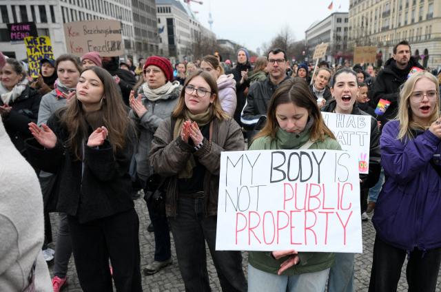 Participants hold up a placard with the lettering reading 'My body is not public property' during a demonstration against sexualized violence against women in Berlin on April 12, 2026. A feminist alliance has called for the demonstration, which is also held in support of German TV presenter and actress Collien Fernandes and all those affected to show: "Enough is enough! Stop the violence against women". The allegations from Fernandes against her ex-husband, actor Christian Ulmen, have sparked intense media debate about the "digital violence" increasingly perpetrated on the internet, mostly against women. The German government has responded to the outcry by pledging to introduce laws to punish the creation and distribution of sexualised deepfakes. (Photo by RALF HIRSCHBERGER / AFP)