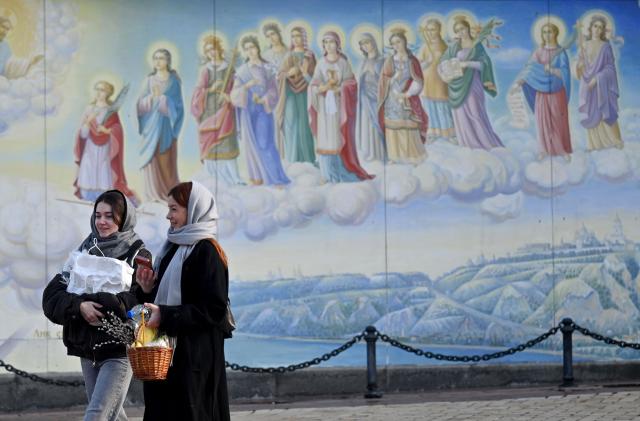 TOPSHOT - Local residents carry their baskets loaded with traditional cakes and eggs after Easter service in Saint Michael's Golden-Domed Cathedral in Kyiv on April 12, 2026, amid the Russian invasion of Ukraine. Ukraine and Russia accused each other on April 12, 2026 of violating a truce in place for Orthodox Easter thousands of times, as the war dragged on into its fifth year. (Photo by Sergei SUPINSKY / AFP)